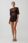 Woman wearing  dark brown shoulder pad short sleeve lace top with matching mini shorts.