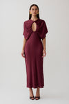 Woman wearing a burgundy cut out satin midi dress.