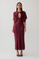 Woman wearing a burgundy cut out satin midi dress.