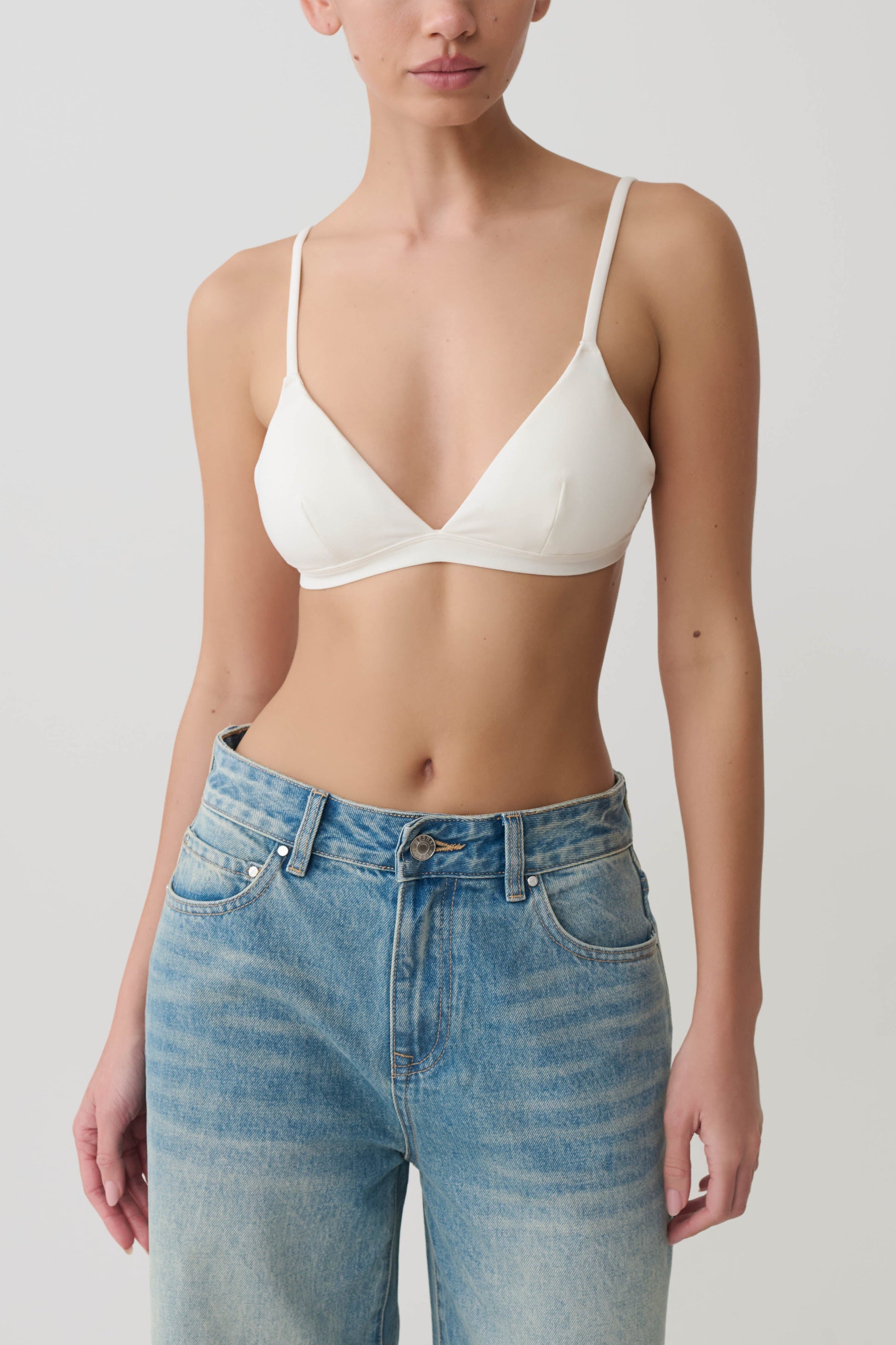 Woman wearing a white micro triangle bralette.