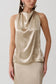 Woman wearing a gold satin halter top.