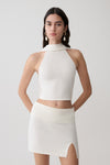 Woman wearing a white halter backless knit top with matching skirt.