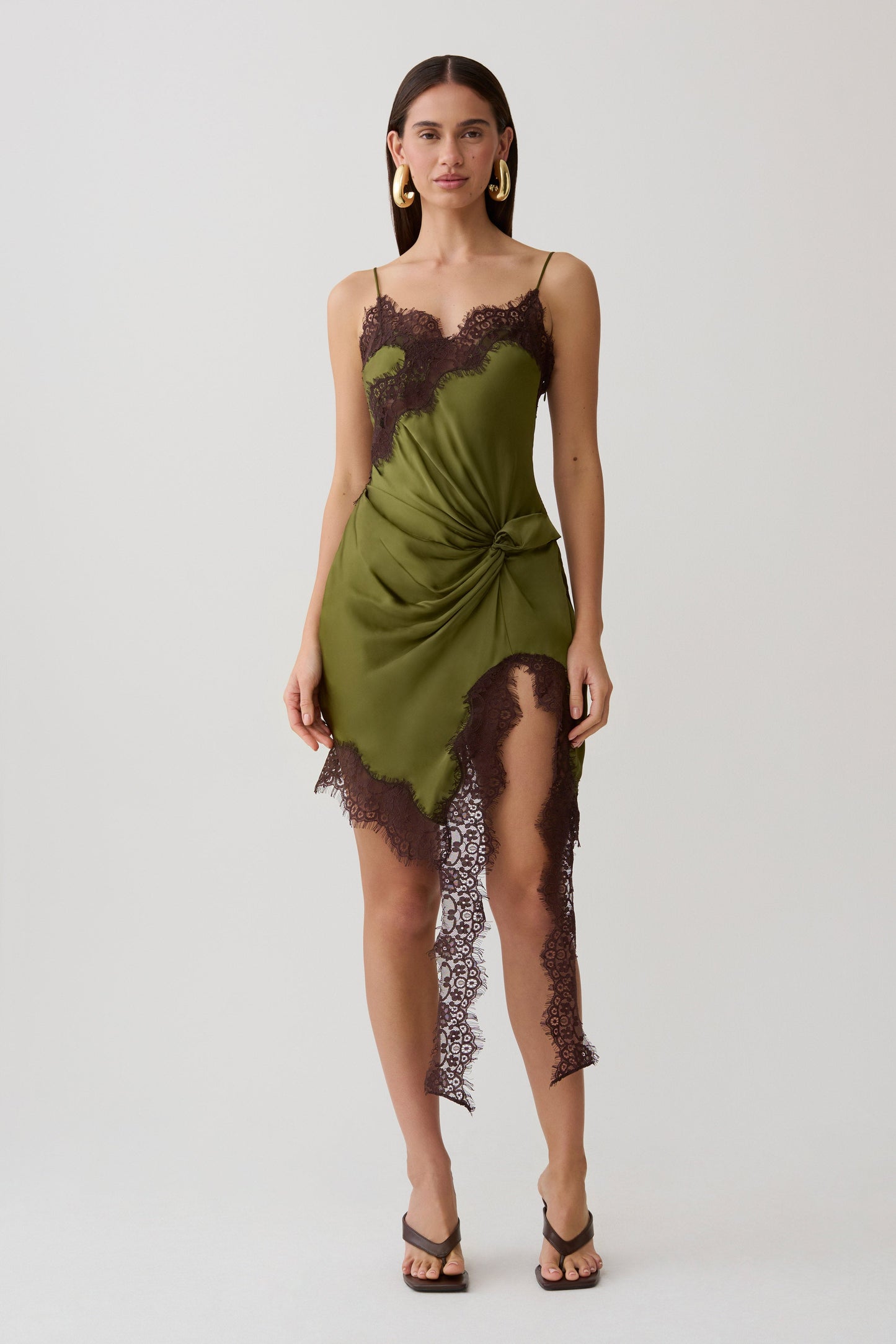 Woman wearing a green and brown satin and lace mini dress.