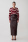 Woman wearing a striped sweater and leather skirt on a white background.