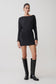 Woman wearing a black dress and knee-high boots on a white background.