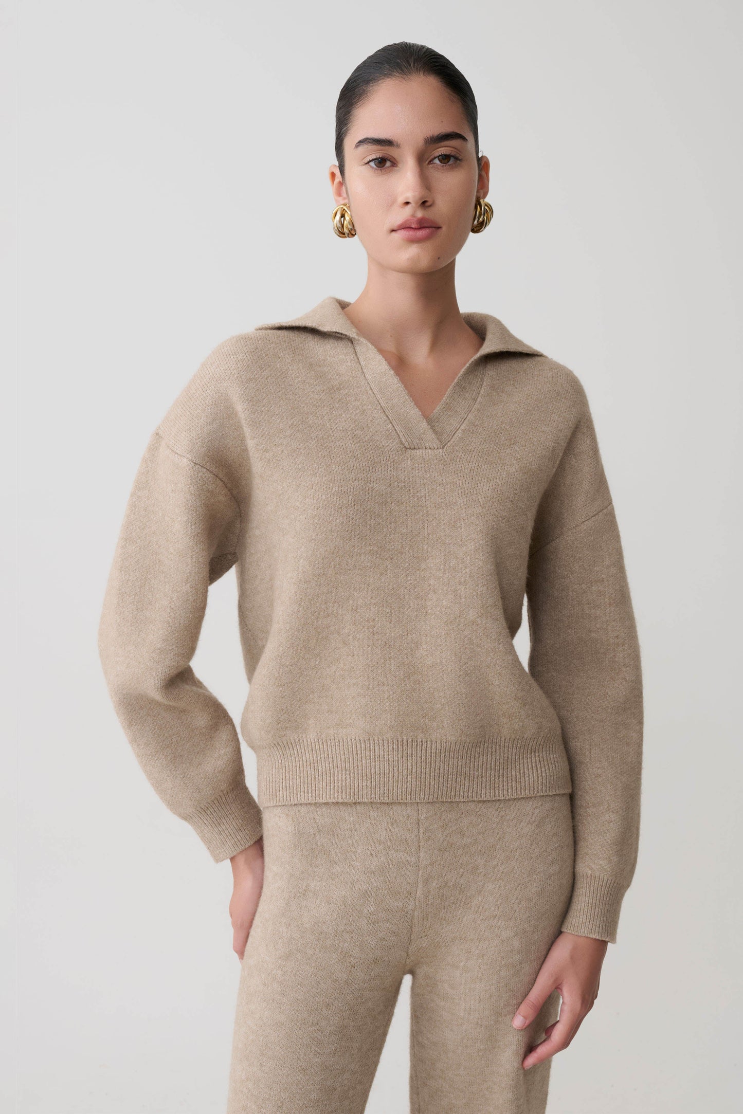 Woman in a beige collared sweater against a white background.