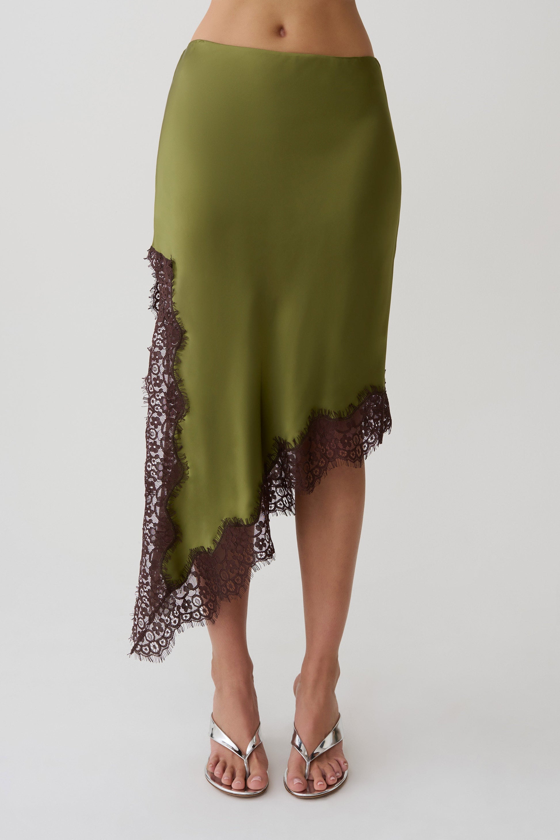 Woman wearing a green and brown satin and lace midi skirt.