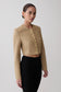 Woman wearing a beige cropped jacket with gold buttons.