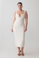 Woman wearing a white ribbed dress on a plain background