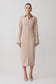 Woman wearing a beige long shirt dress on a white background