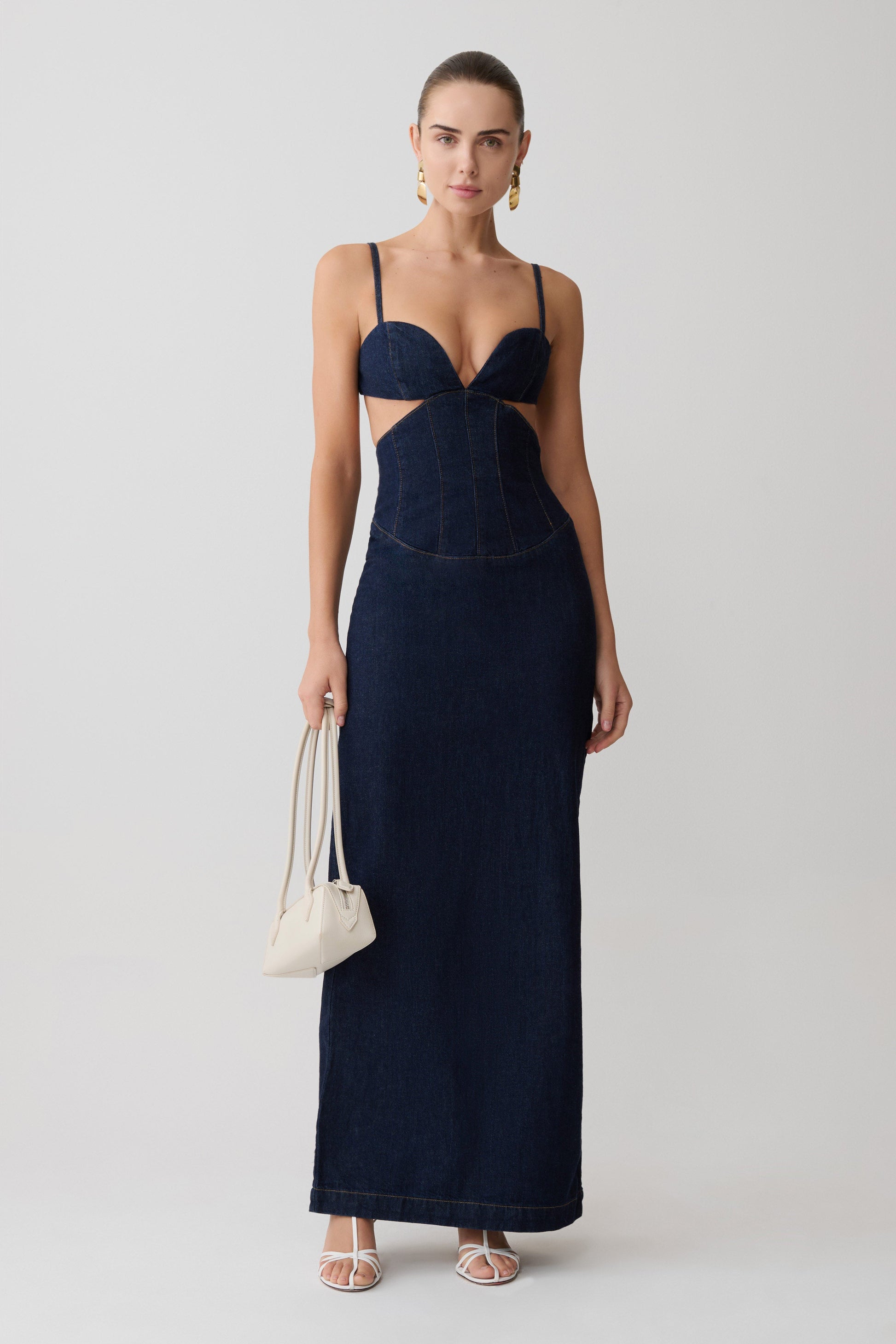 Woman wearing a navy blue dress with cut-out design on a white background