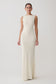 Woman wearing a long, off-white dress against a plain background