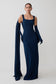 Woman wearing a long navy blue dress with a cape on a white background