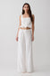 Woman wearing a white embroidered top and tie pant set.