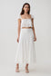 Woman wearing a white lace sleeveless crop top with matching panelled midi skirt.