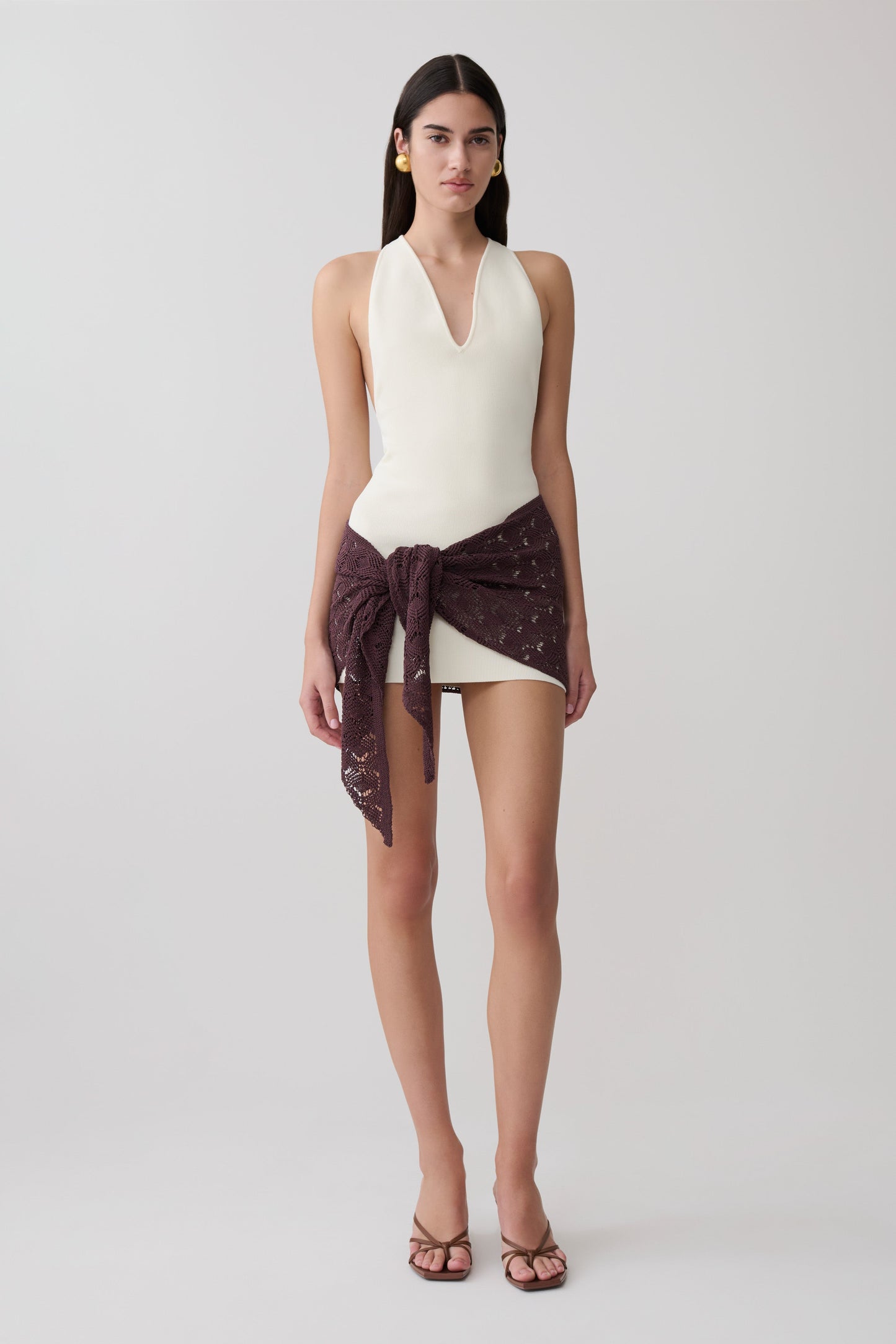 Woman wearing a white mini Dress with a brown crochet overlay.