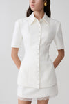 Woman wearing white button up short sleeved top.
