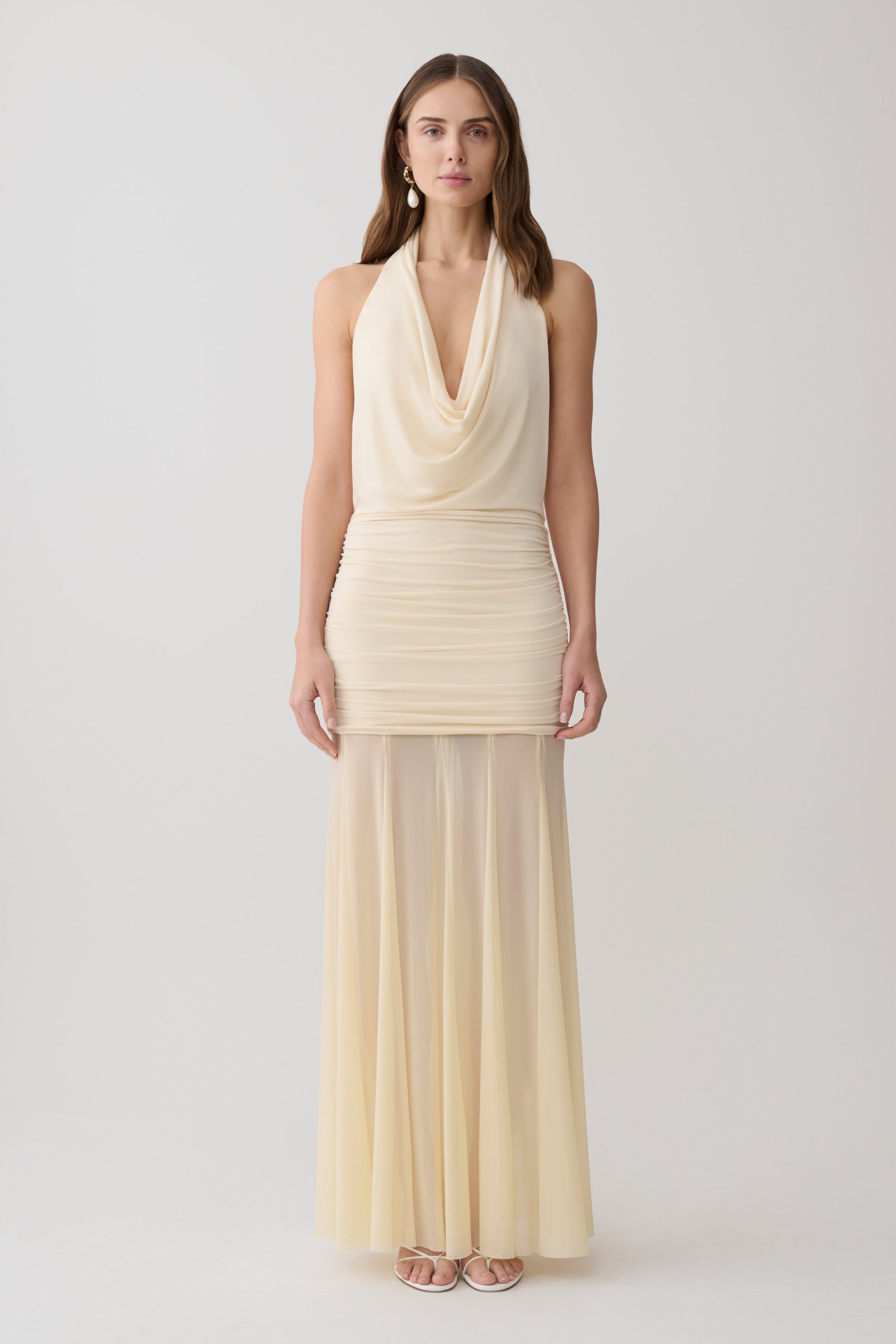 Woman wearing a white draped halter slinky maxi dress.