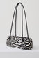 A zebra-print cylindrical shoulder bag with black double shoulder straps, displayed on a clean white studio background.