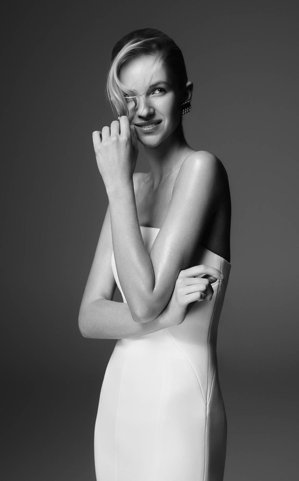 Black and white portrait of a woman in a white dress against a dark background.