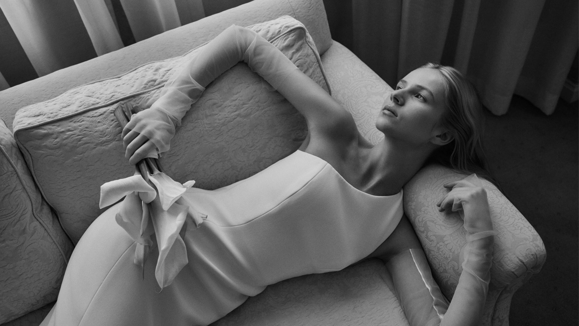Woman lying on a couch with a wedding gown.