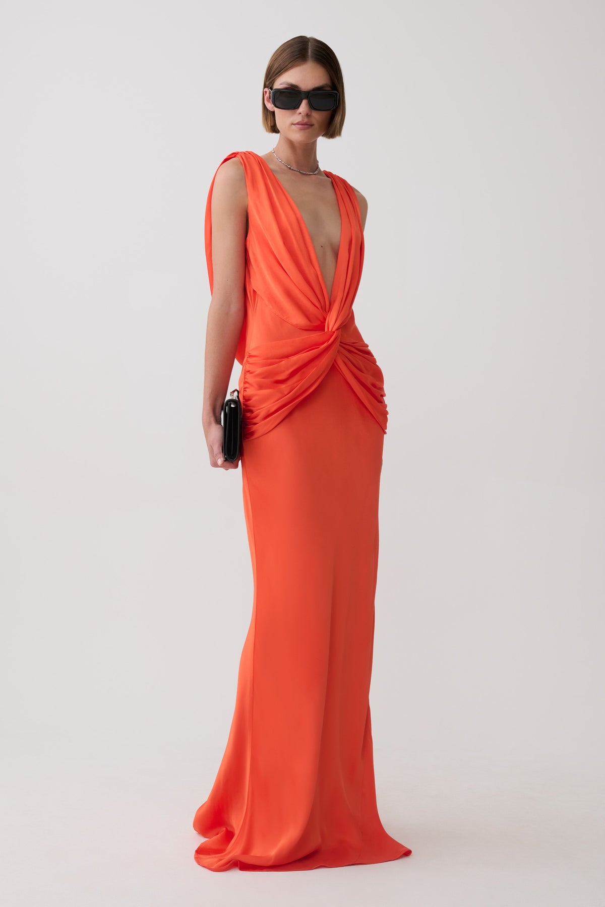 Woman wearing an orange v neck satin maxi dress.