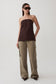Woman wearing a strapless brown top and olive green twill denim cargo pants.