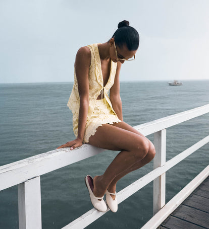 Image of woman sitting on pier wearing yellow top and skirt set