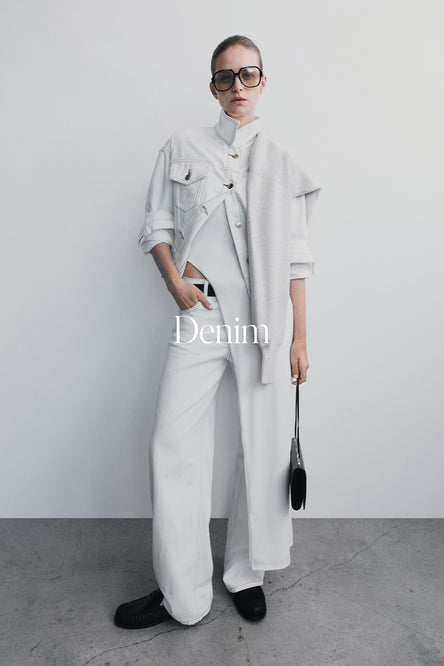 Person wearing a white denim outfit with sunglasses against a plain background.