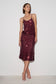 A woman modeling a sleeveless, spaghetti-strap top with matching midi skirt covered in dark burgundy sequins, standing against a plain white studio background.