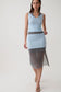 A woman modeling a sleeveless light blue wrap-style dress with a sheer dark gray overlay skirt, photographed against a plain light gray studio background.