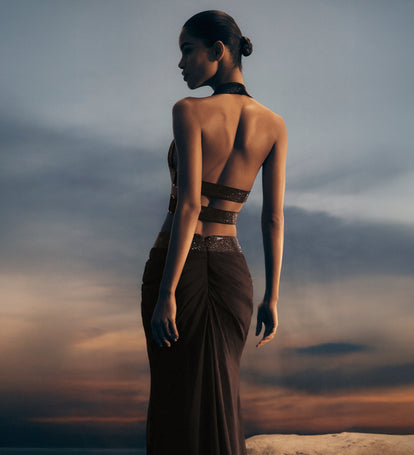 Woman in a dark dress standing against a dramatic sky.