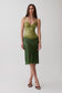 A woman models a green lace midi dress with a corset-style bodice and spaghetti straps, paired with black heeled sandals, against a plain light gray studio background.